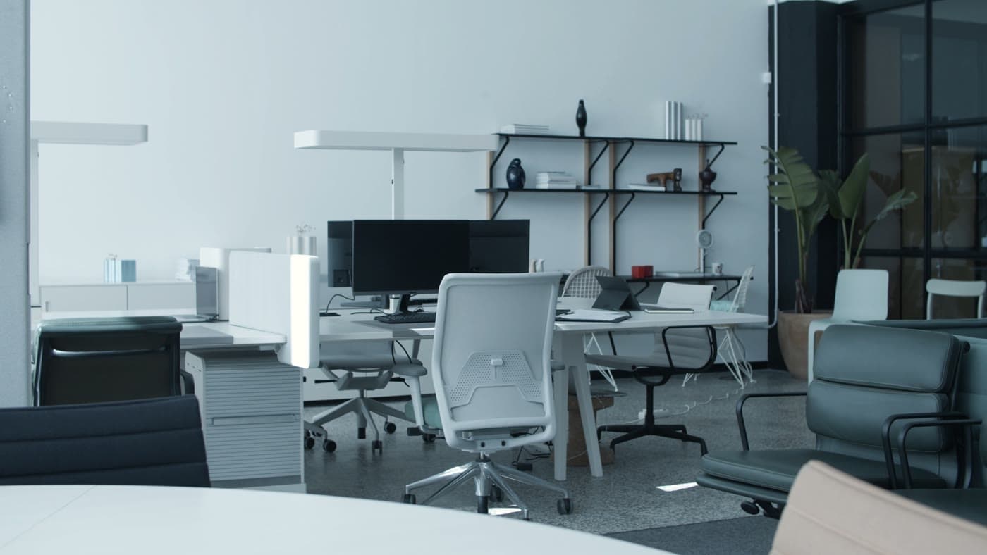 An empty open-plan office with desks, monitors and chairs ready for the working day